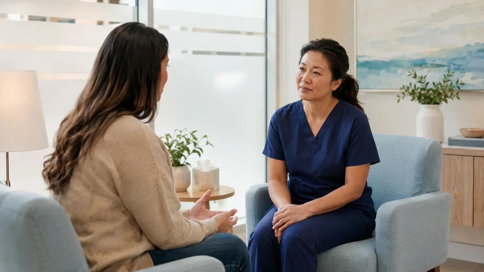 Adult patient speaks privately with an attentive nurse in a bright, calm consultation room.