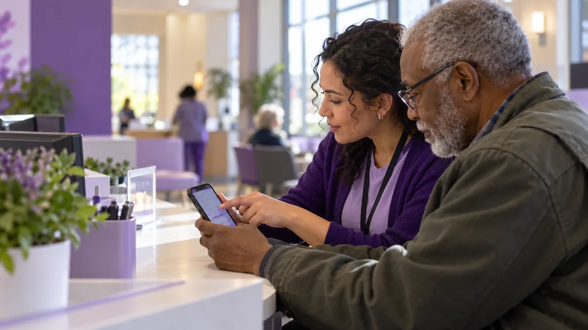 A digital navigator helps an older man set up his patient portal on his phone.