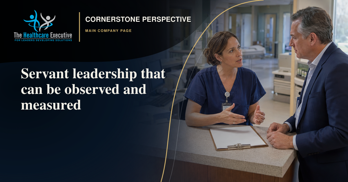 A senior healthcare leader listens closely to a nurse at a hospital workstation, representing observable servant leadership.