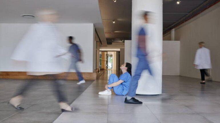 Exhausted Nurse in Hospital Corridor Amid Staffing Crisis